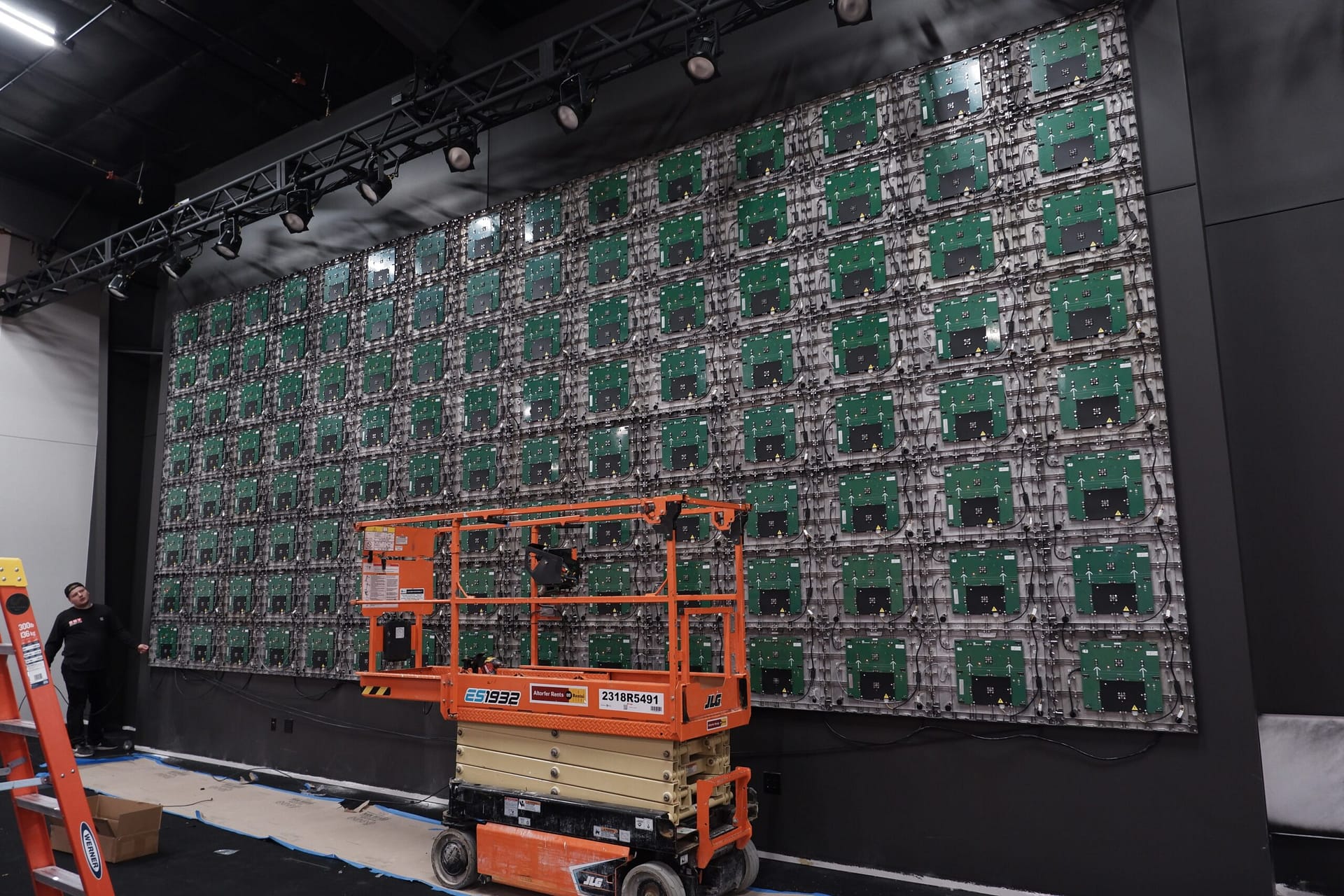 LED video wall panels being installed with rear panel electronics visible and Limitless AVL crew working below