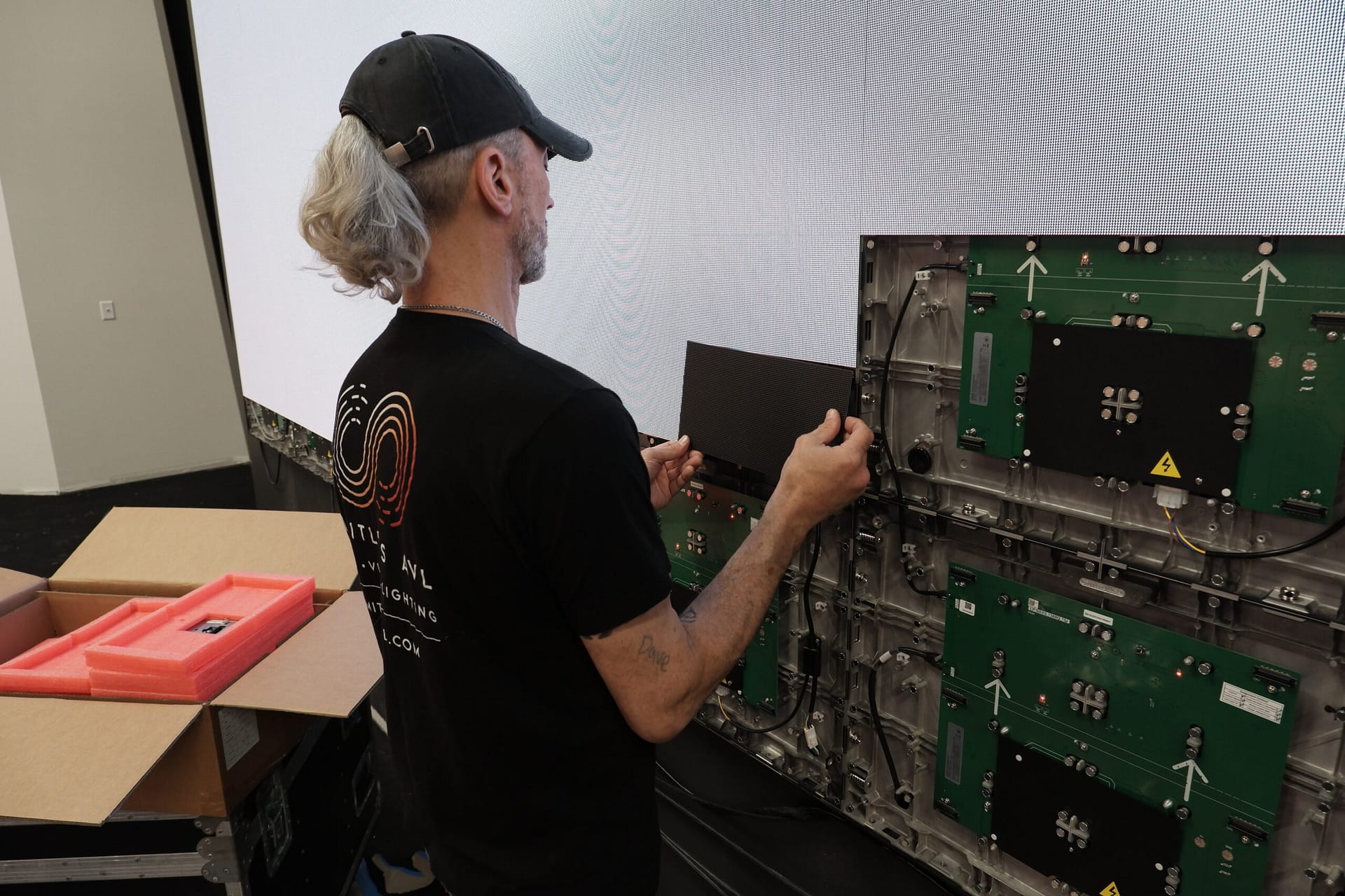 Limitless AVL technician handling an LED video wall panel during installation